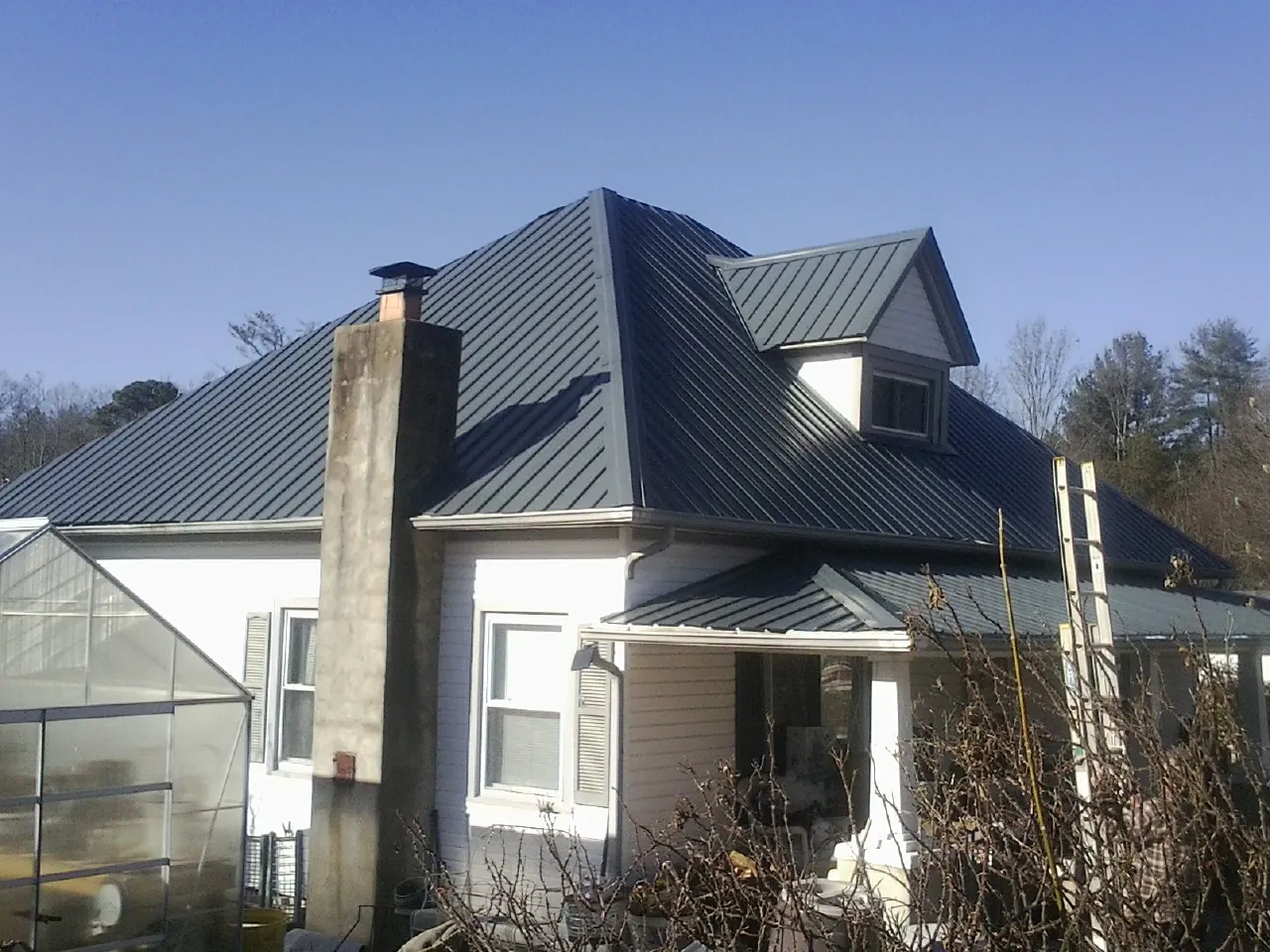 Dark blue standing seam metal roof on a white farmhouse with dormer — Slate & Tile Roof Repair by Roofing Brothers in Weippe