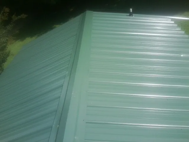 New green metal panels meeting at the ridge of a roof — Flat Roof Repair work by our crew in Weippe