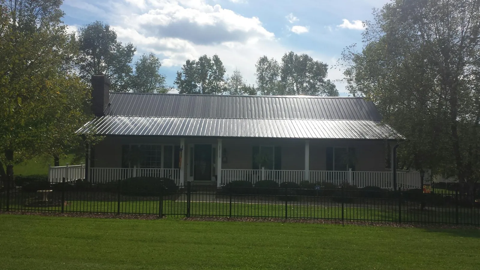 Gray metal roof on a brick ranch with a full width front porch — Gutter Guard Installation work by our crew in Weippe